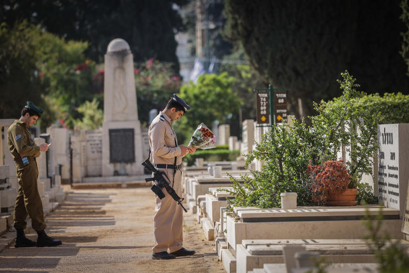 חיילים ליד קבר מחזיקים פרחים