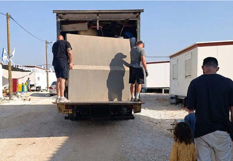 הסבלים פורקים את המשאית בכניסה לבית משפחת בר־טל ביישוב כדים