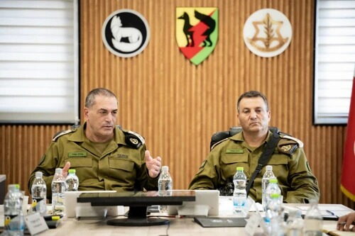 שני קצינים בכירים יושבים מול סמלי אוגדת עזה