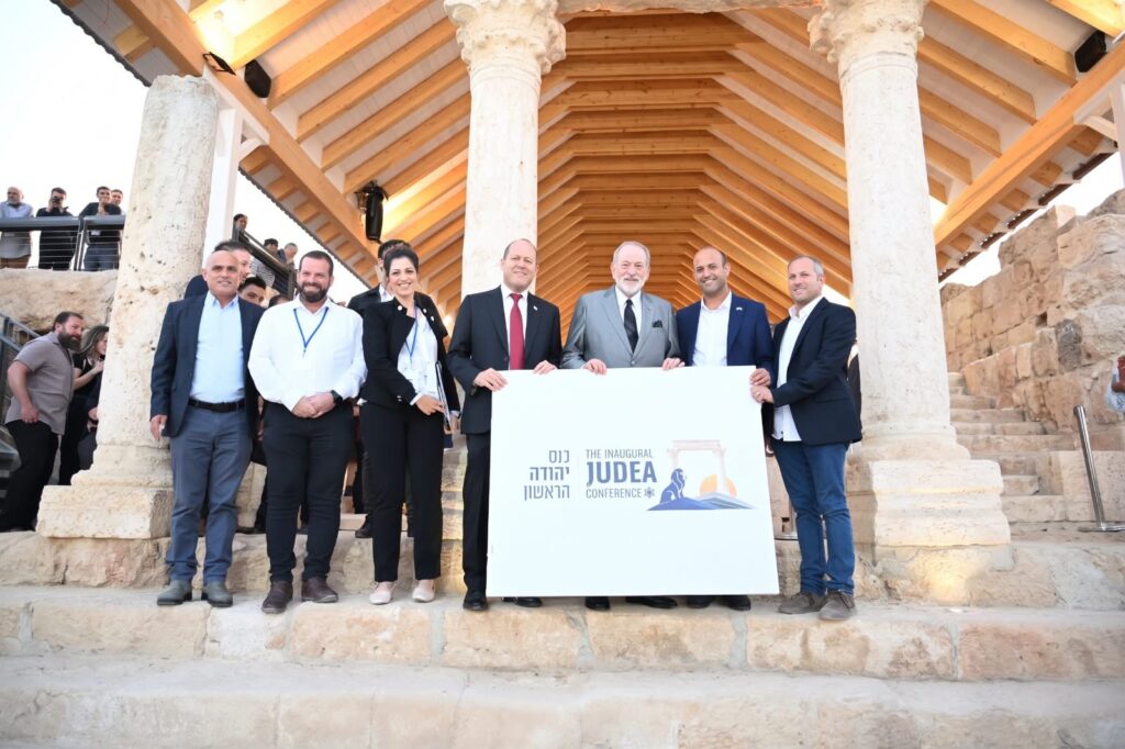 קבוצת אנשים מחזיקה שלט כנס יהודה הראשון