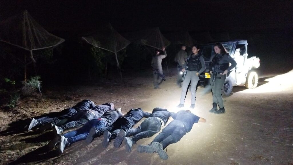 שוהים בלתי חוקיים שוכבים על הקרקע ולצדם שוטרי מג"ב