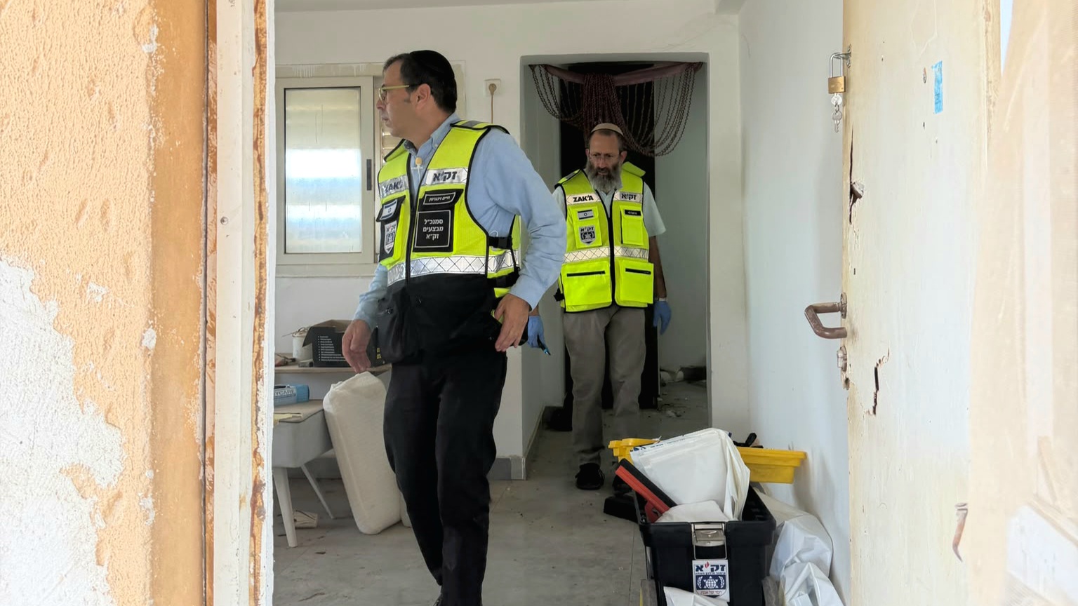 מתנדבי זק"א נכנסים לדירה ועוברים בין החדרים עם ציוד איסוף