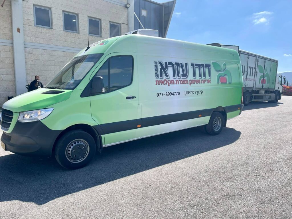 רכב הובלה ירוק של סטופ מרקט עם לוגו הרשת וטלפון הזמנות
